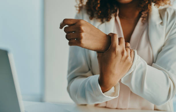 A woman sitting at a computer rubs her wrist that hurts because of carpal tunnel syndrome.